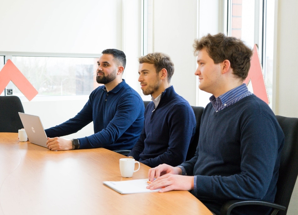 Drie mannen die aan tafel zitten.